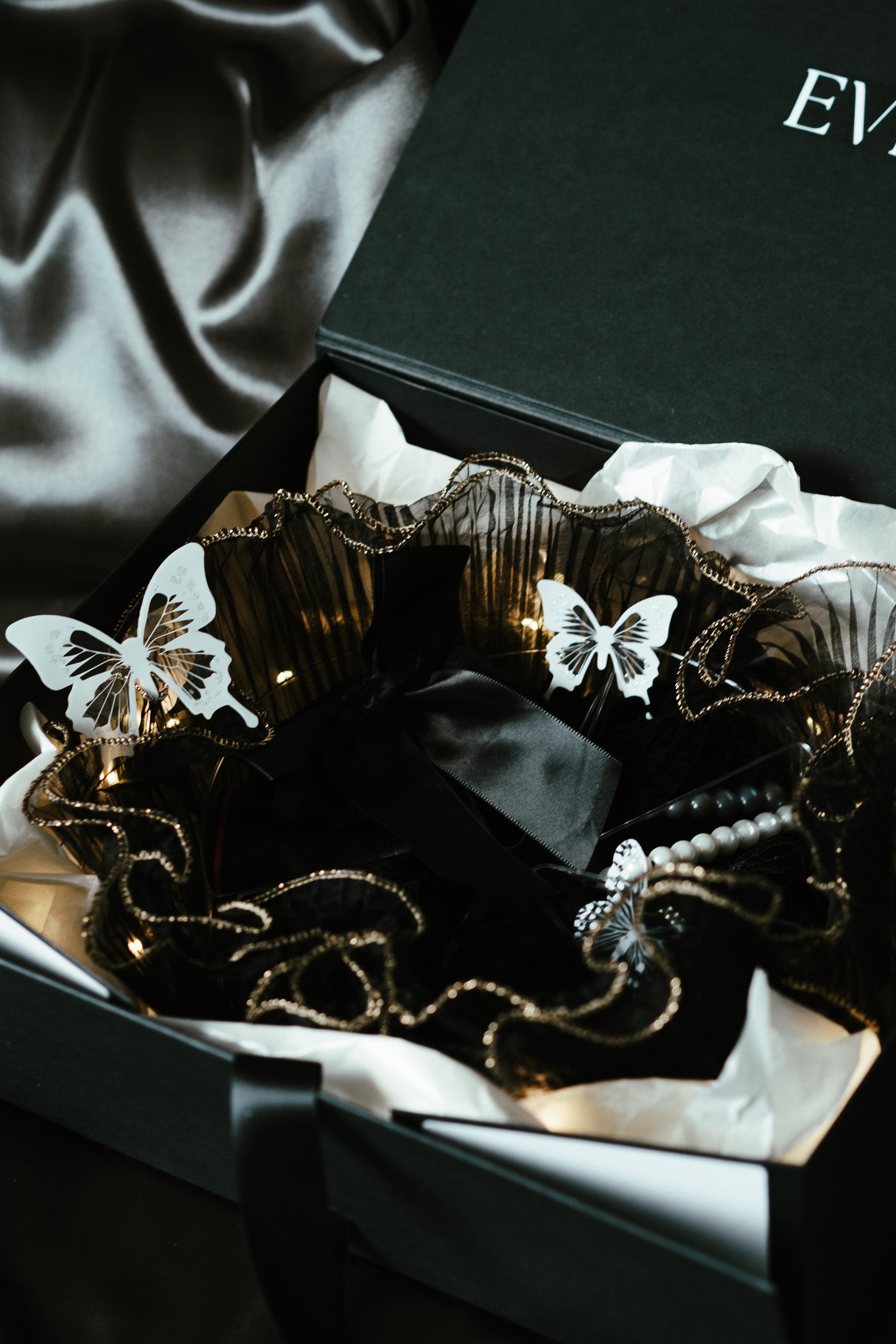 Decorative lingerie gift set with butterflies in a black box on a satin surface
