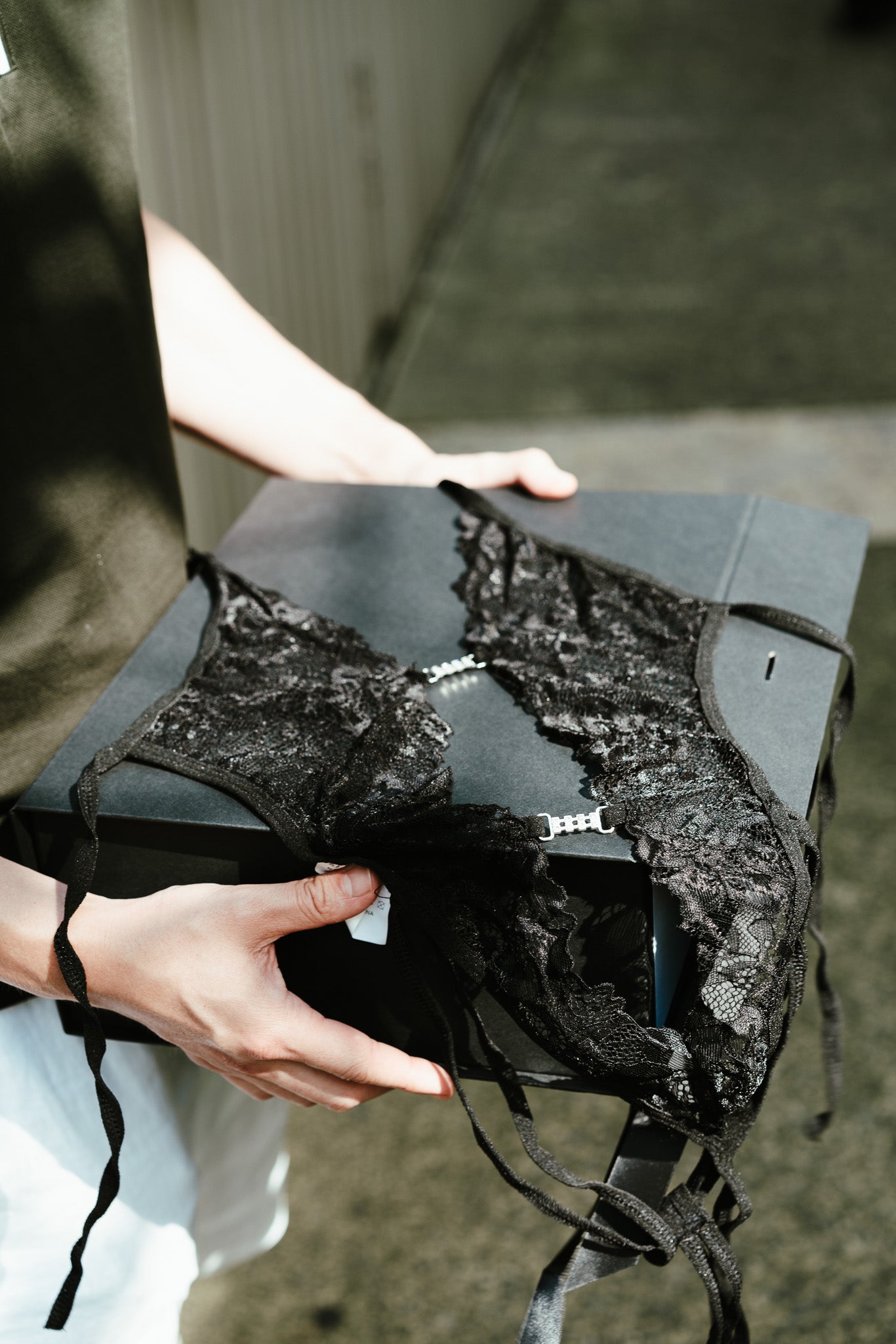 Person holding a black lace lingerie with a blurred background