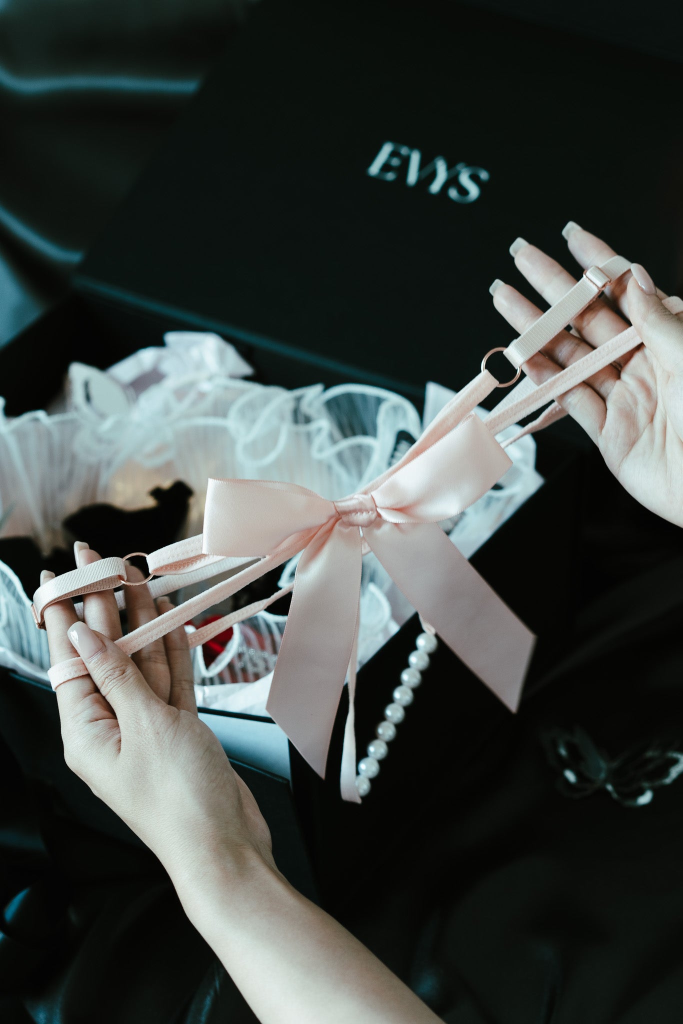 Person holding a pink bow with a black background